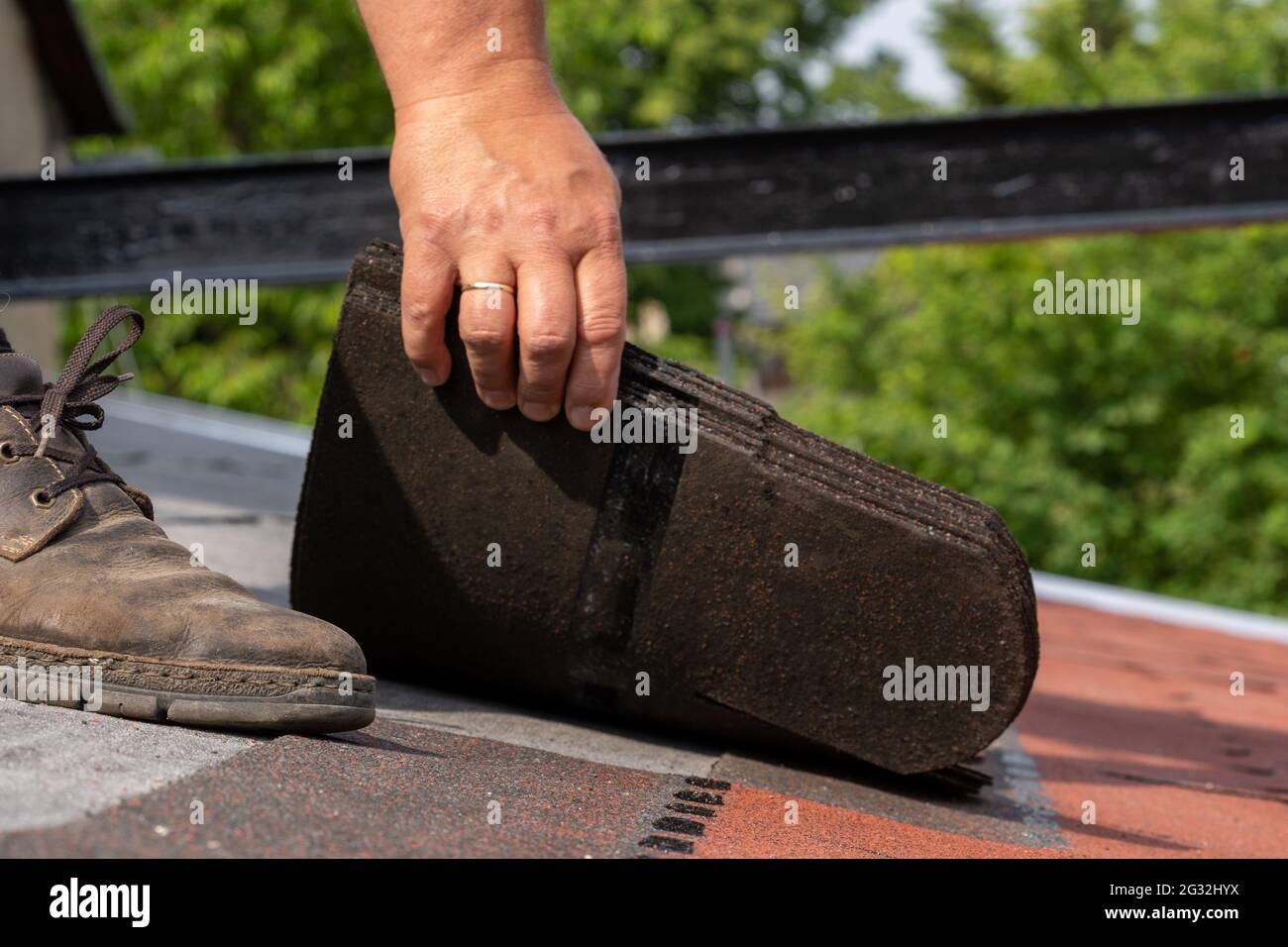 Die Hände des Mitarbeiters sind beim Einbau von Bitumendachschindeln angebracht Stockfoto