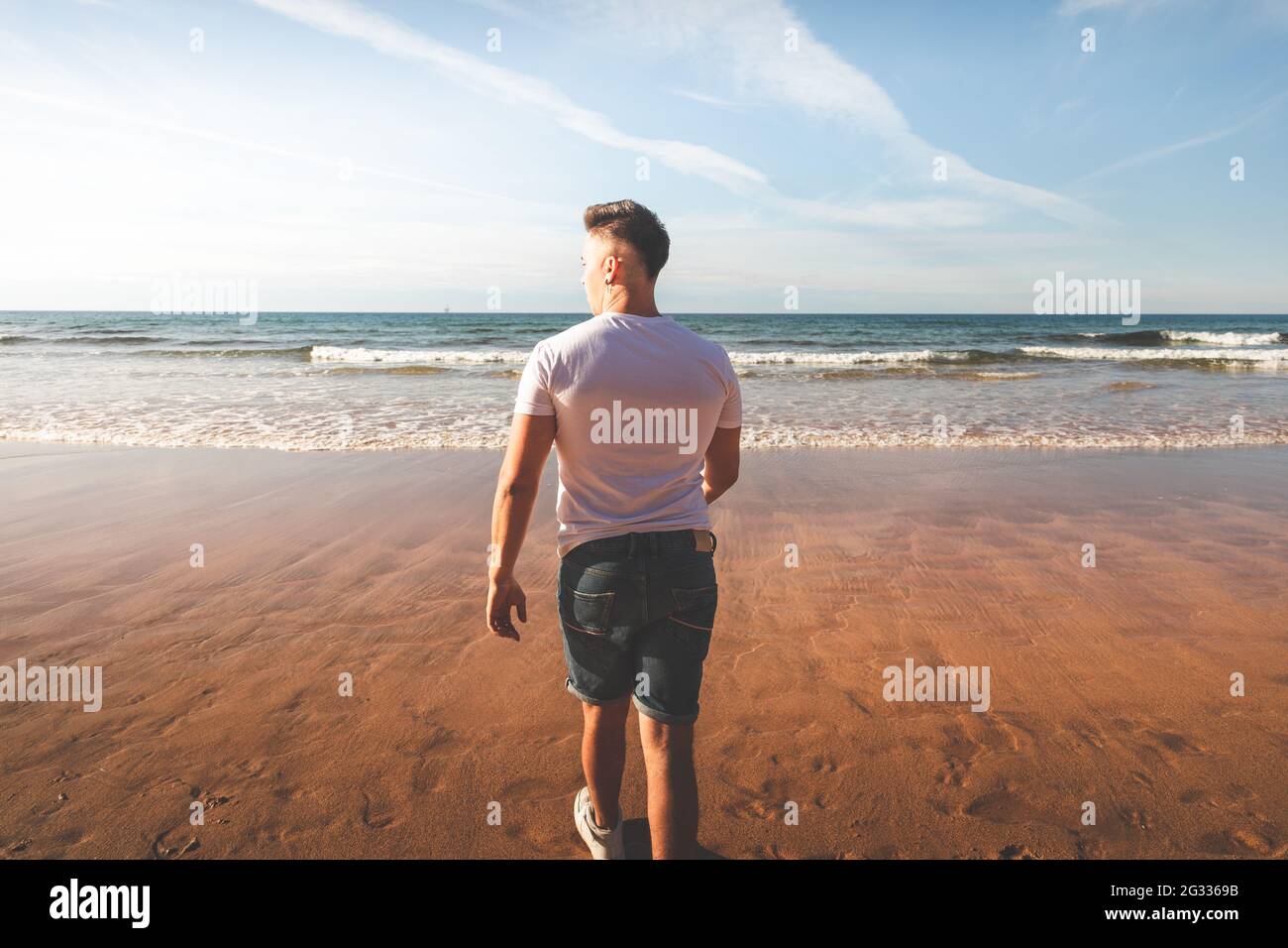 Junger Kaukasier, der am Strand läuft Stockfoto