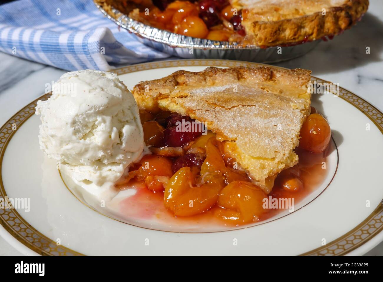 Ein Stück Kirschkuchen aus einem frisch hausgemachten Kirschkuchen mit Rainer und dunklen roten Kirschen, serviert mit Vanilleeis Stockfoto