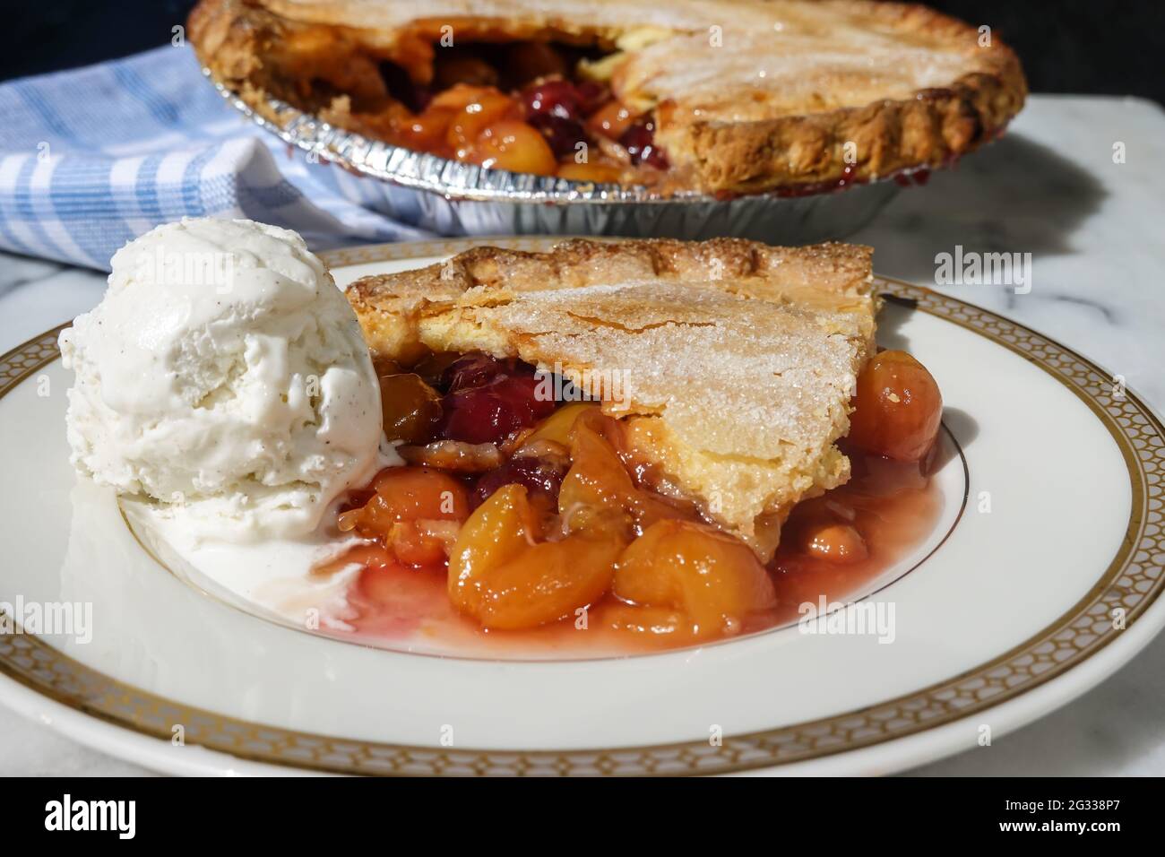 Ein Stück Kirschkuchen aus einem frisch hausgemachten Kirschkuchen mit Rainer und dunklen roten Kirschen, serviert mit Vanilleeis Stockfoto