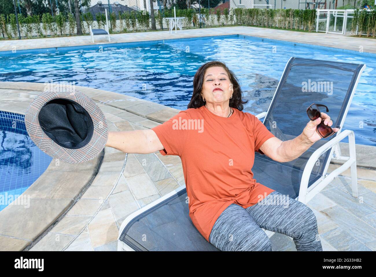 74-jährige ältere Frau am Pool, glücklich mit ihrem Ruhestand. Stockfoto