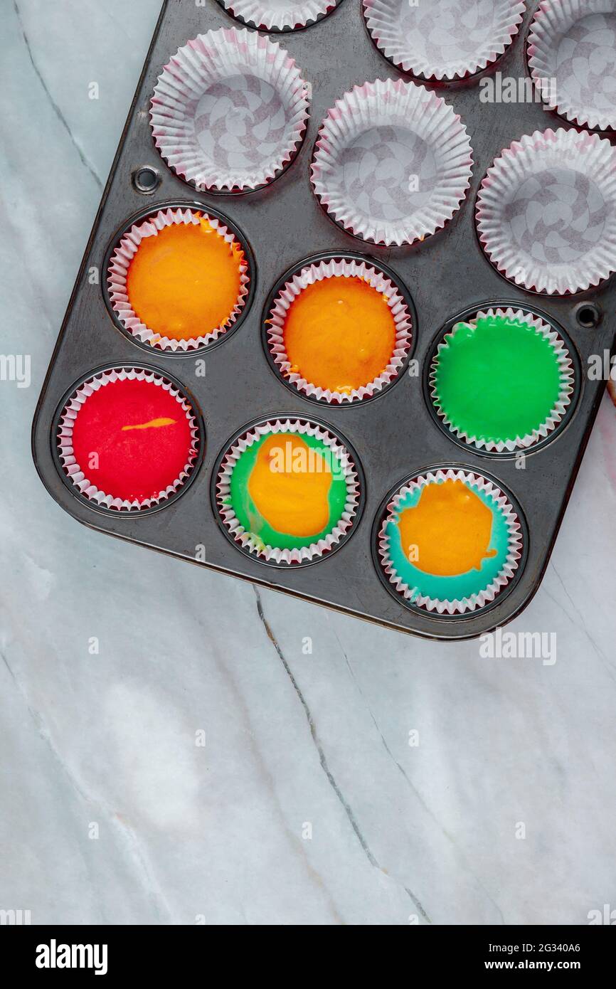 Hausgemachte Regenbogen-Cupcakes auf dem Backblech. Draufsicht. Stockfoto