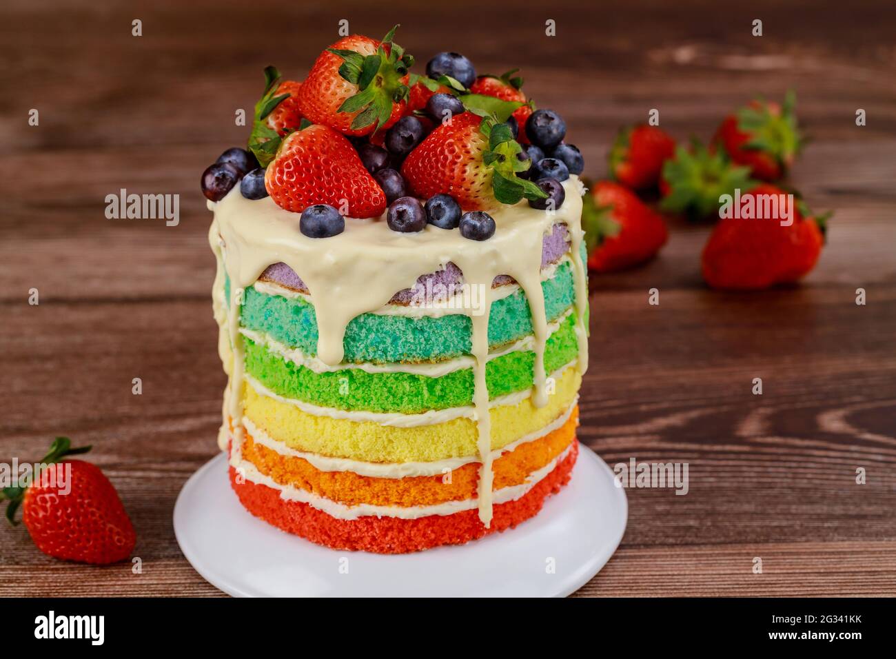 Regenbogen-Biskuitkuchen mit frischen Beeren verziert. Stockfoto