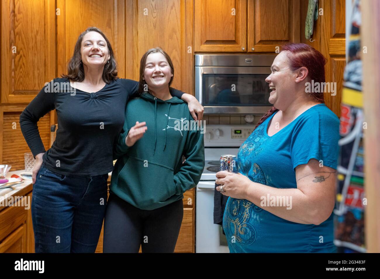 Mutter, 15-jährige Tochter und Schwägerin, die sich in einer Küche freundlich unterhalten. (MR) Stockfoto