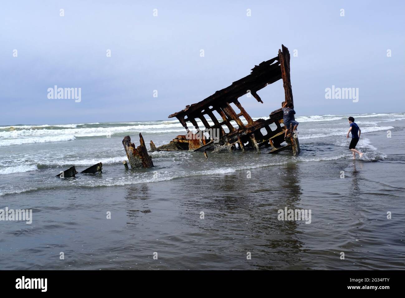 Touristen laufen, um das Wrack des Peter Iredale im Fort Stevens State Park in Astoria, Oregon, zu sehen und zu erklimmen Stockfoto