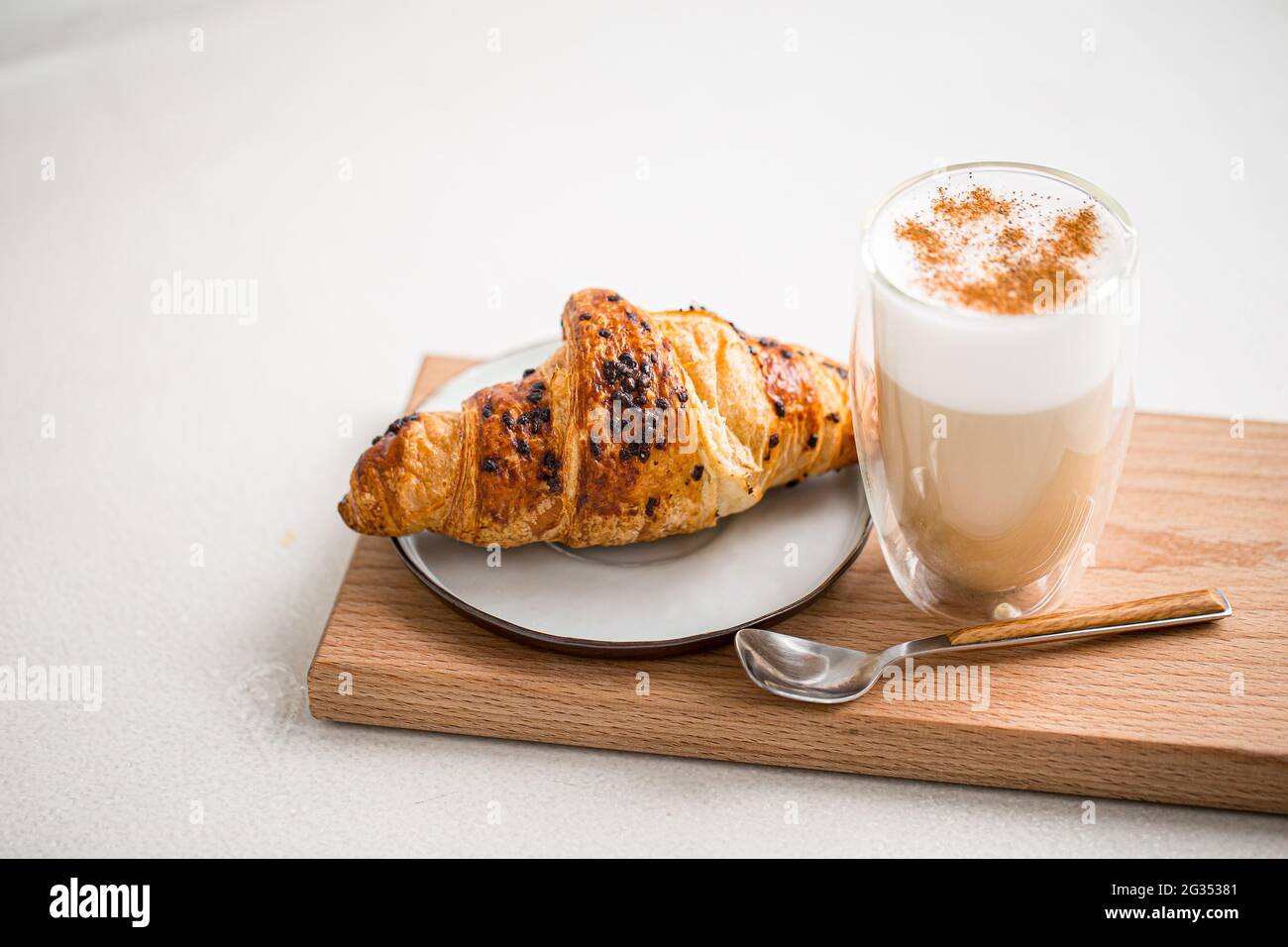 Glas Kaffee Latte mit Zimt und Croissant Stockfoto