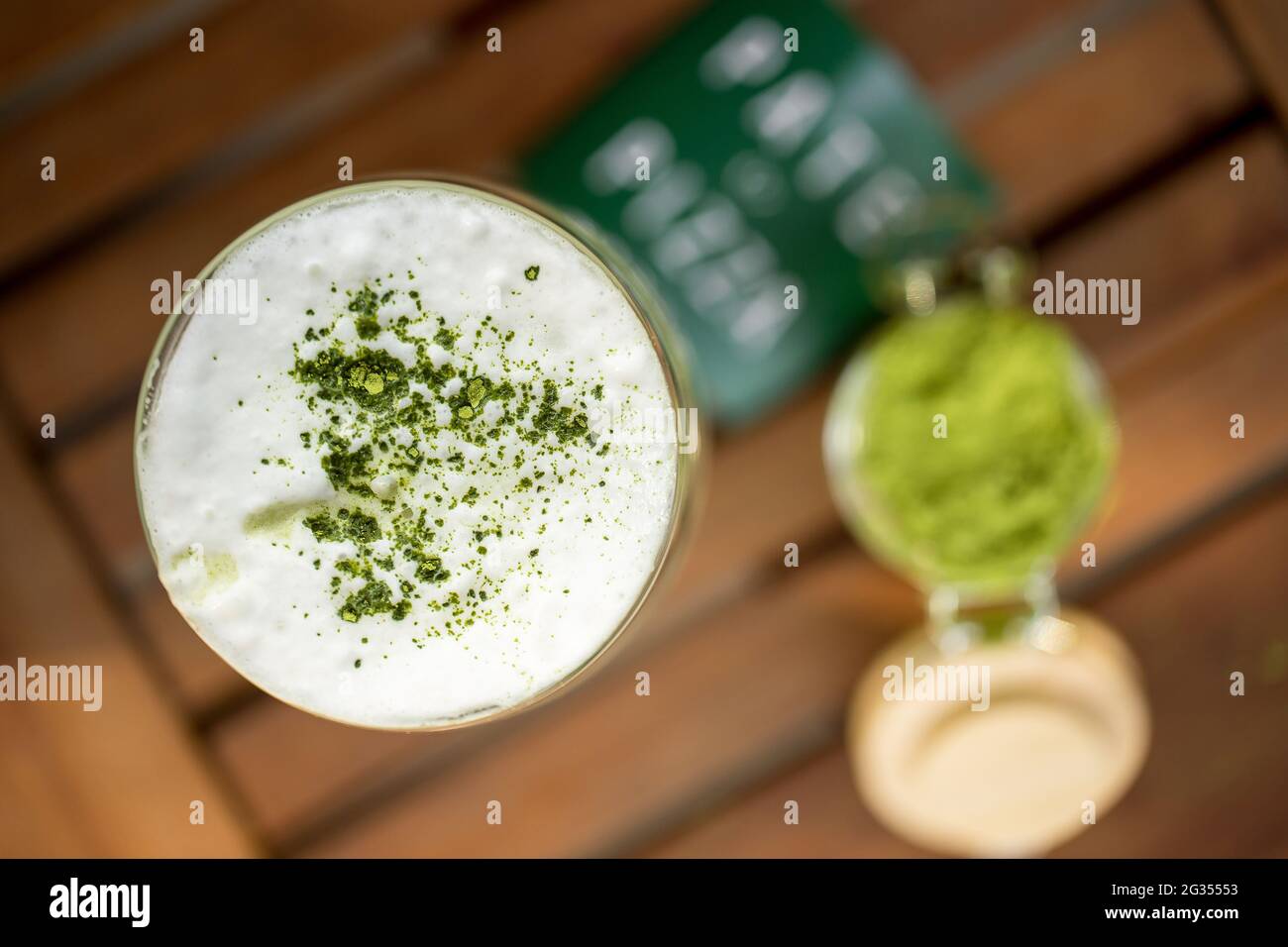 Matcha Grüner Tee Latte mit Schaum auf Holztisch Stockfoto