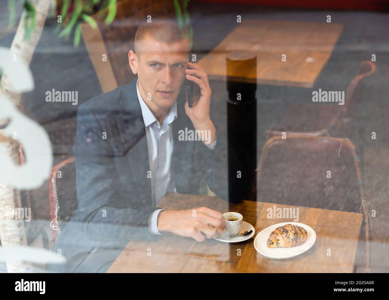 Geschäftsmann, der im Café sitzt und telefoniert Stockfoto