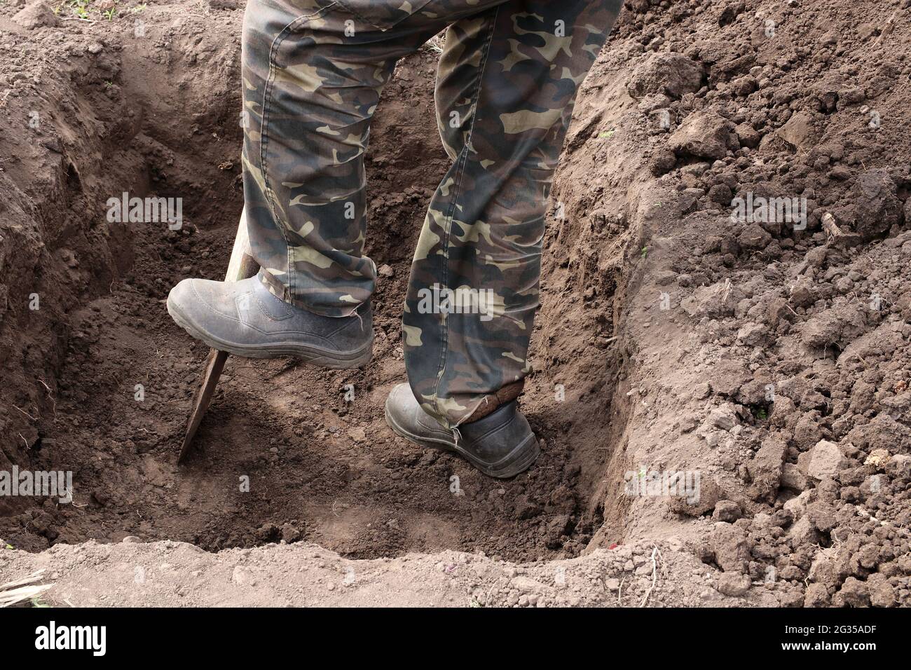 Der Mann gräbt eine tiefe Grube. Graben einer Grube durch Schaufel. Stockfoto