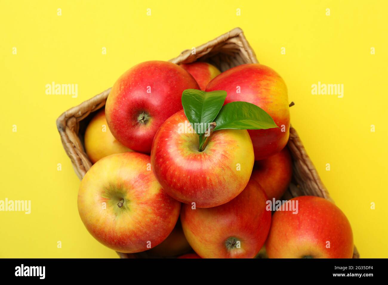 Korb mit roten Äpfeln auf gelbem Hintergrund Stockfoto
