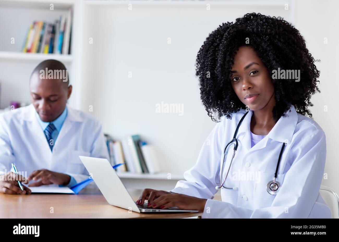 afroamerikanische Medizinstudentin, die mit einem männlichen Wissenschaftler im Krankenhaus am Computer arbeitet Stockfoto