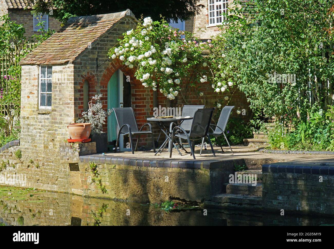 Backsteingebäude am Kai und am Fluss mit Tisch und Stühlen. Stockfoto