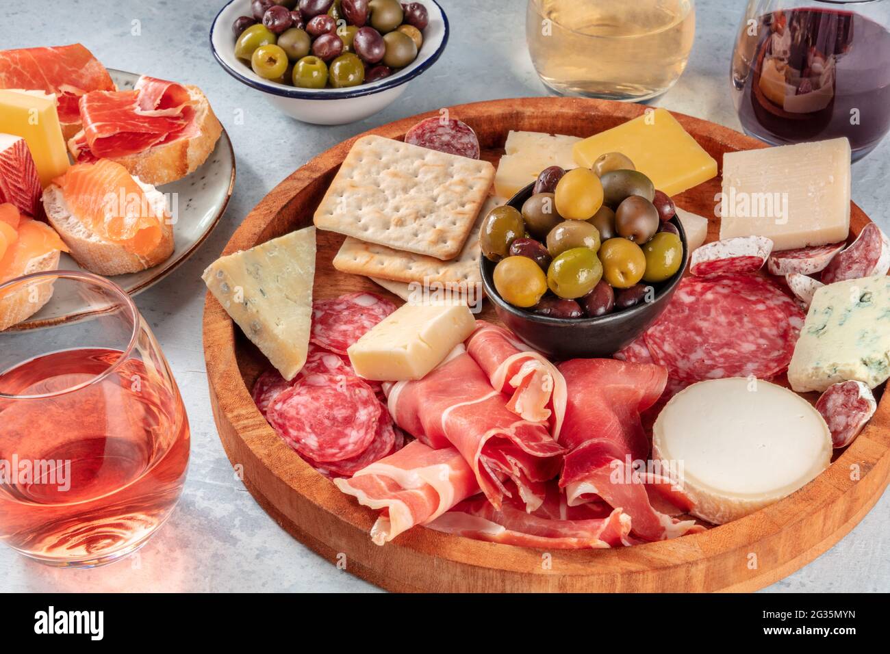 Italienische Antipasti oder spanische Tapas mit Wein. Wurstplatte mit Prosciutto, Jamon, Käse, Salami, Lachs-Sandwiches und Oliven Stockfoto