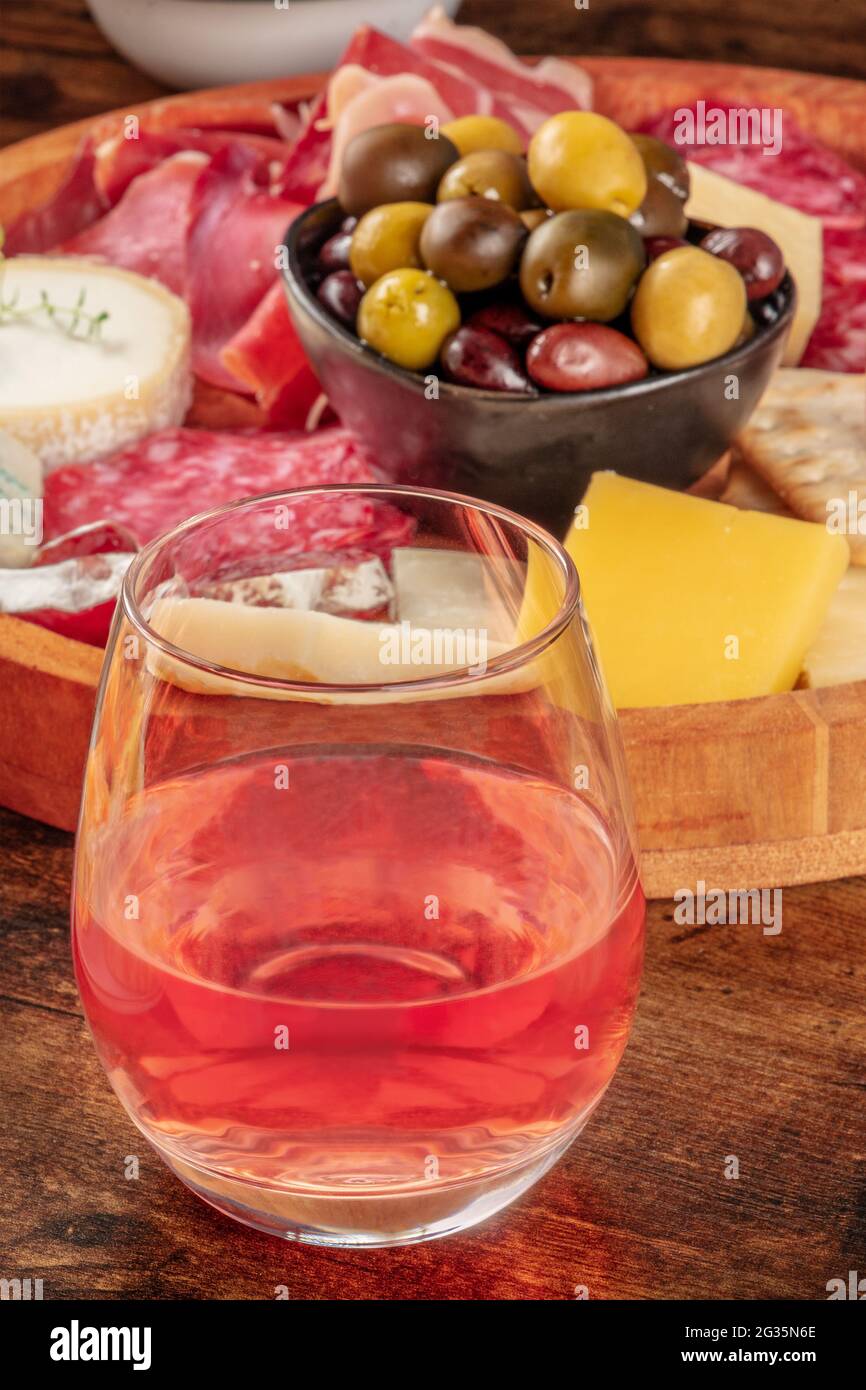Ein Glas Roséwein, Nahaufnahme vor einem Käseplatte mit Oliven. Ein Getränk in einer Bar mit Antipasti oder Tapas. Gourmet-Essen Stockfoto