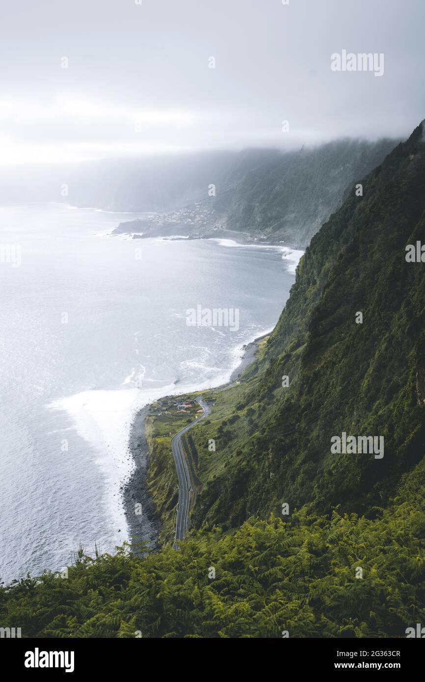 Wolken über der Küstenstraße, umgeben von üppiger Vegetation der Berge, Seixal, Insel Madeira, Portugal Stockfoto