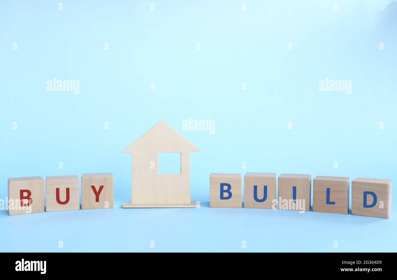 Kaufen oder bauen Sie ein Hauskonzept. Holzhausmodell mit Holzblöcken auf blauem Hintergrund. Stockfoto