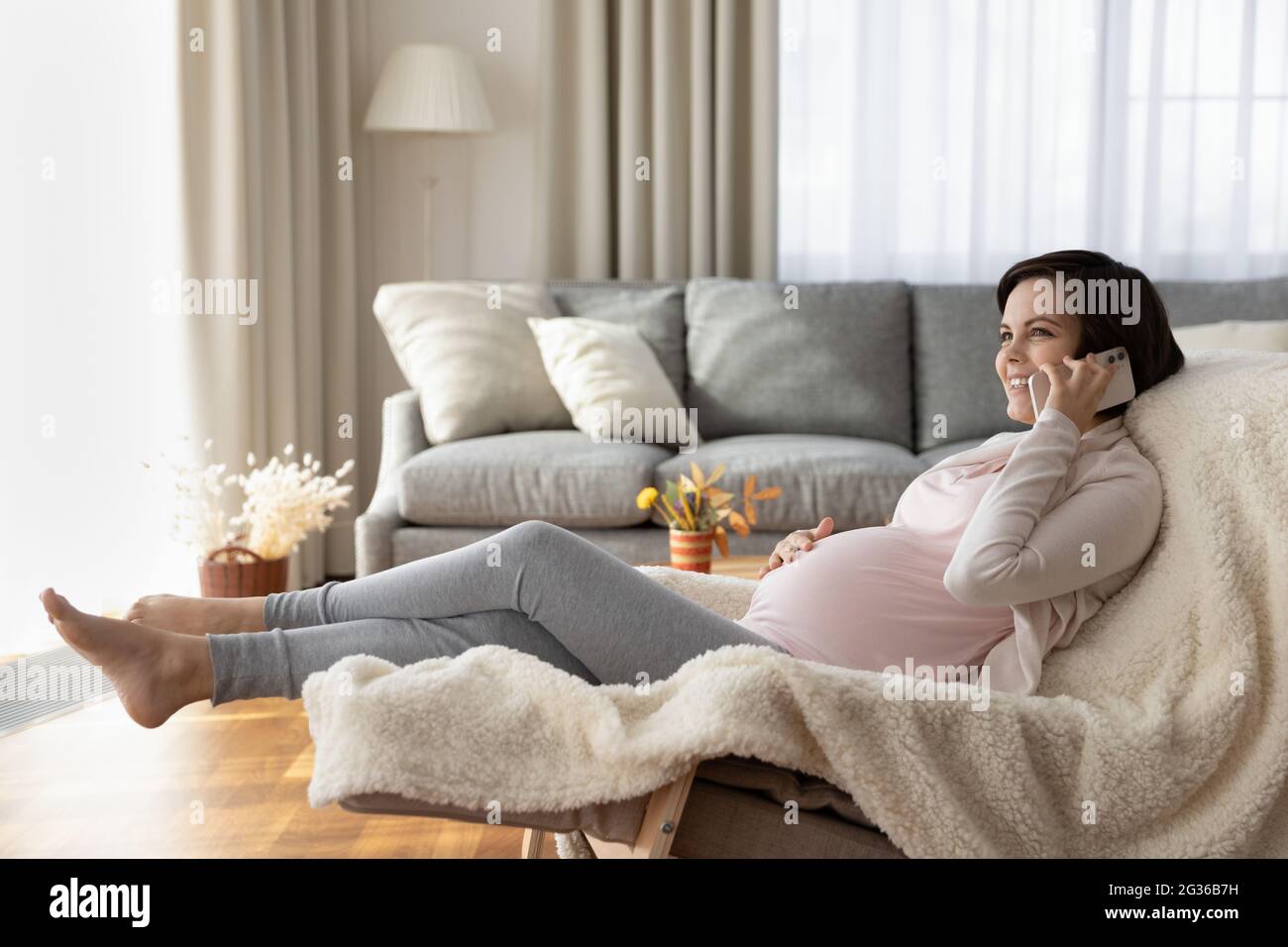 In voller Länge glücklich schwanger Frau chattet am Telefon zu Hause Stockfoto
