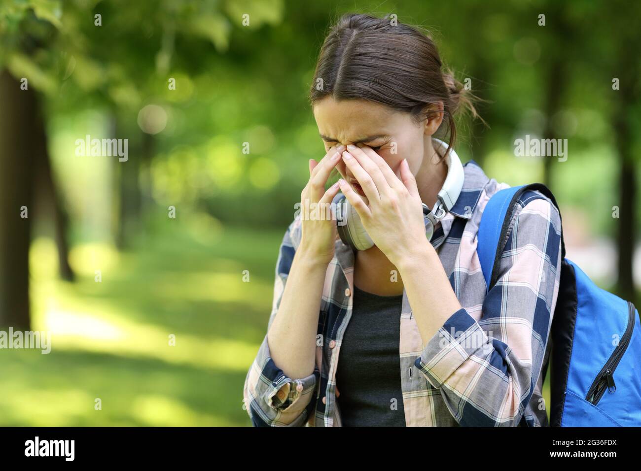 Schüler mit Allergiesymptomen kratzen juckende Augen in einem Park oder Campus Stockfoto