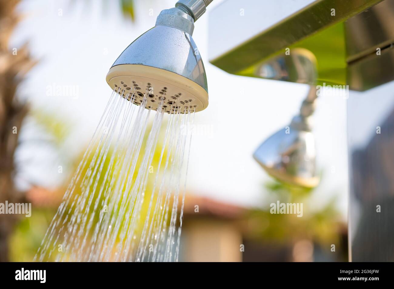 Erfrischender Duschkopf im Freien, der Wasser spritzt, um vor dem Schwimmen im Pool oder im Meer im Resort zu duschen. Stockfoto