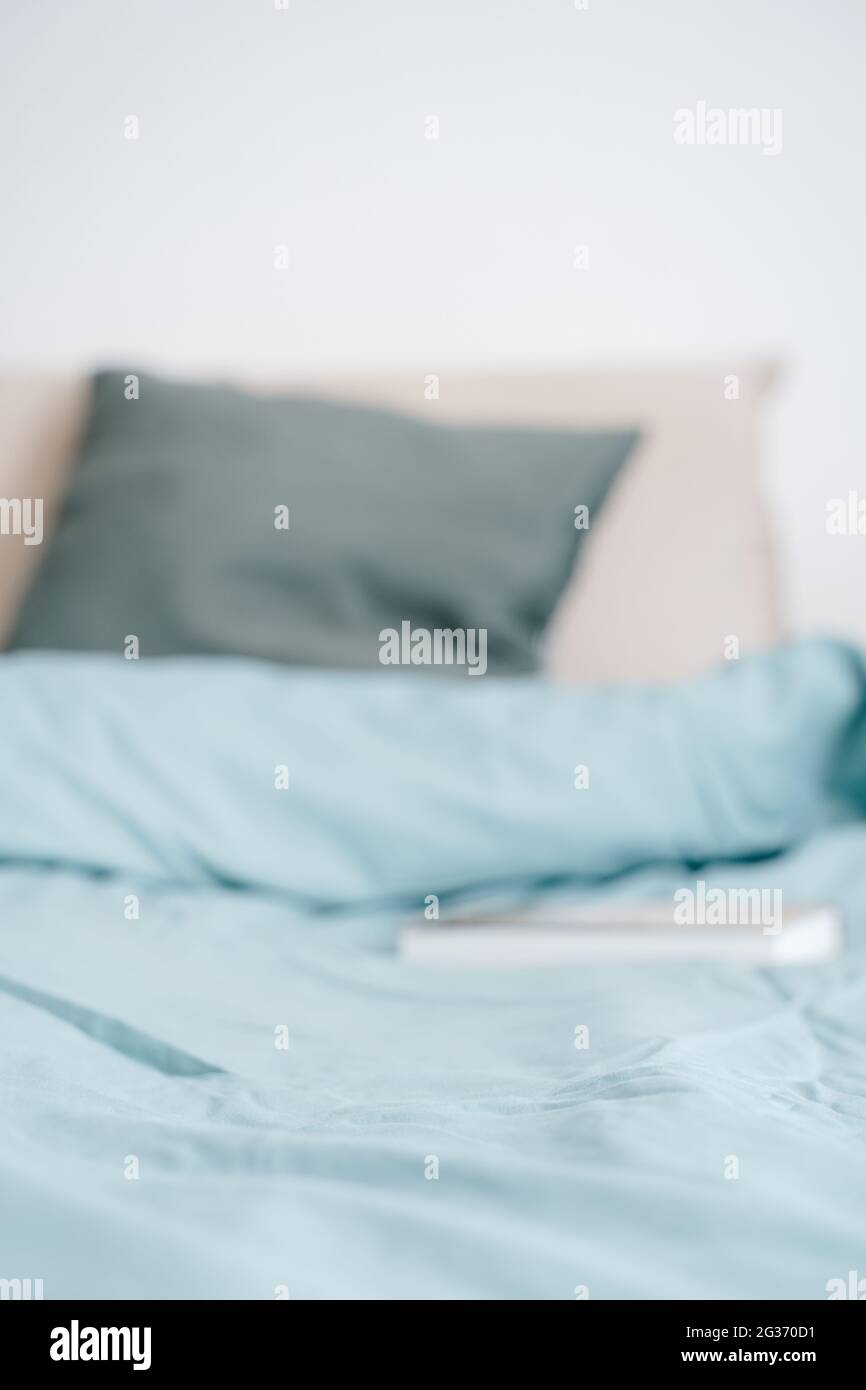 Bett und Kissen mit Buchhintergrund in Blau und Gold verschwommen. Schlaf- und Gesundheitskonzept Stockfoto