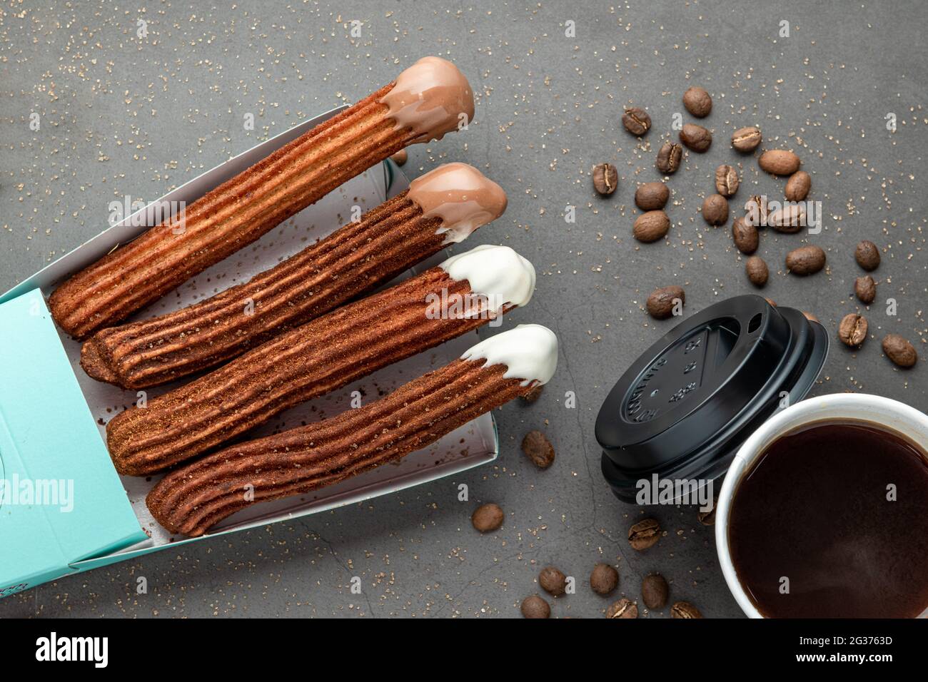 Blick von oben auf Kaffee zum Mitnehmen neben Schokolade gefüllt und einfache Churros. Stockfoto