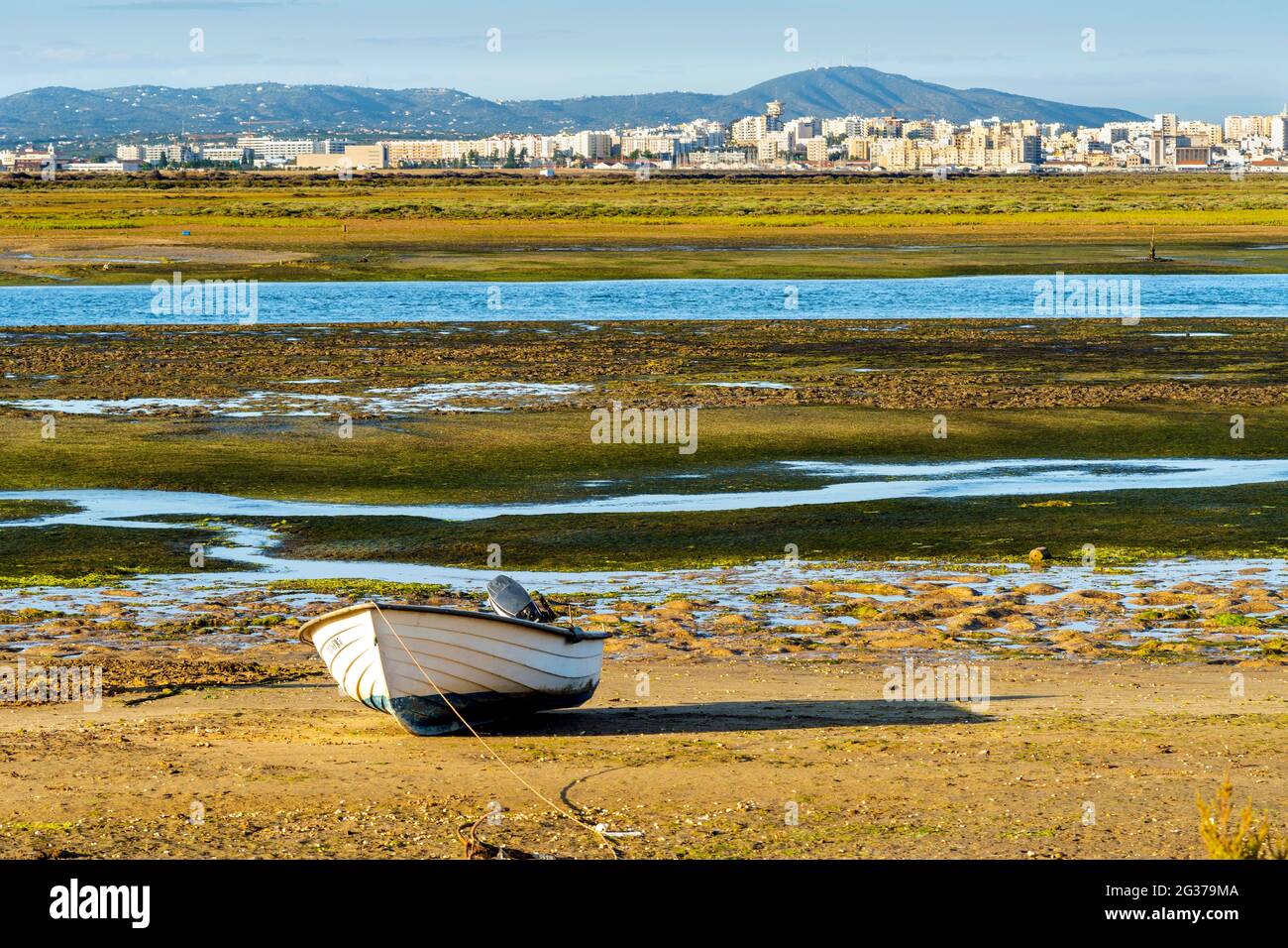 Boot durch die Feuchtgebiete der Ria Formosa bei Ebbe, Stadt Faro im Hintergrund, Algarve, Portugal Stockfoto