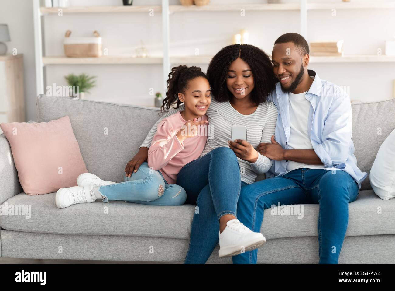 Glückliche afroamerikanische Familie hält und mit Smartphone zu Hause Stockfoto