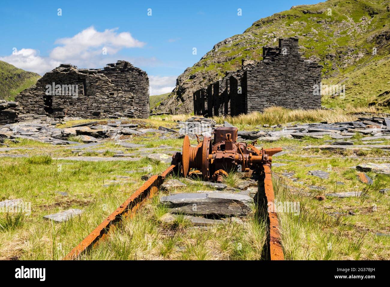 Alte rostige Windmaschine durch verfallene Ruinen der Rhosydd Schiefersteinbruch Steinbruchbaracken in Bwlch y Rhosydd in den Moelwyn Bergen von Snowdonia Wales Stockfoto