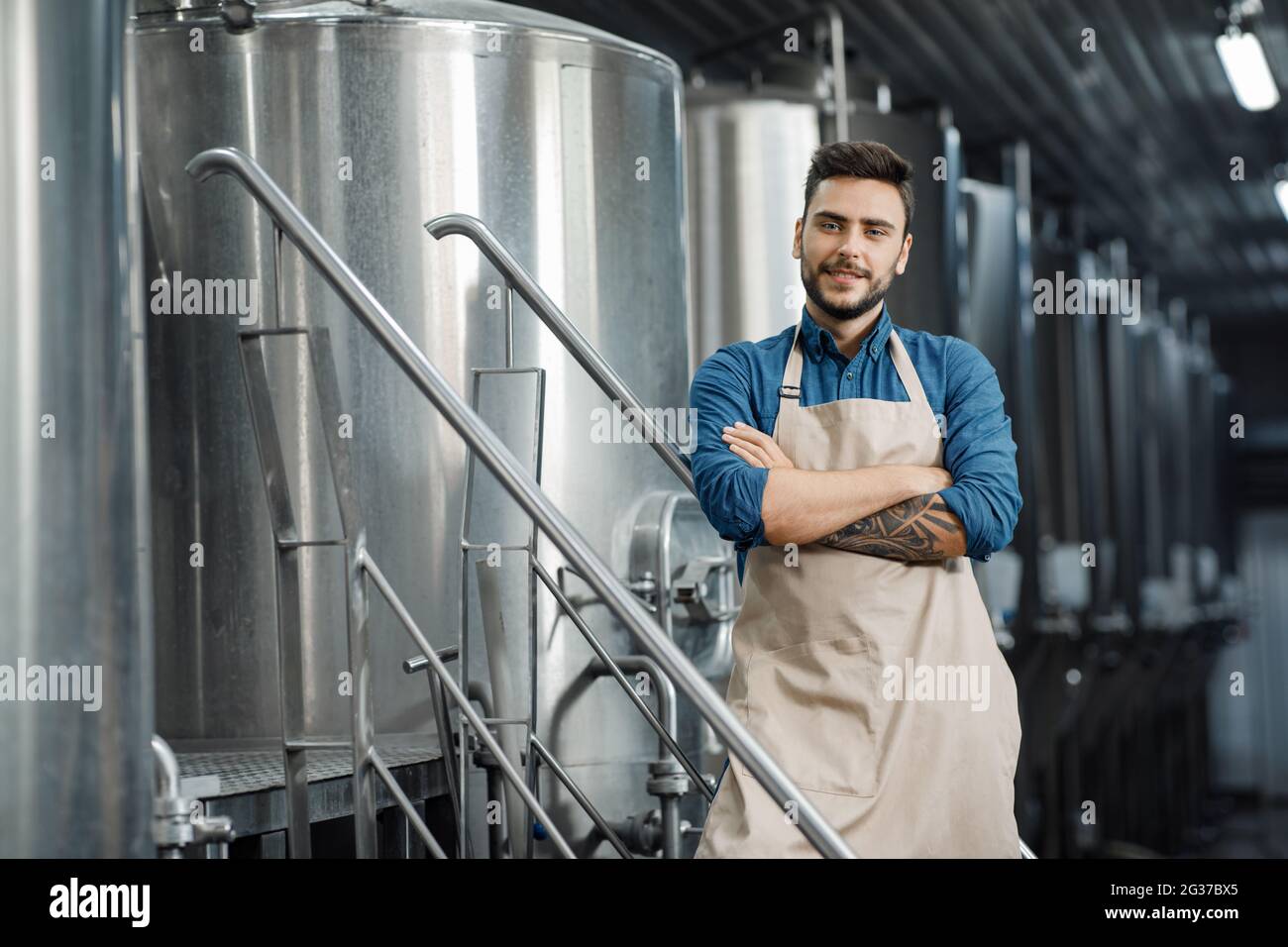 Brauer mit großem Metallbehälter in der Brauereifabrik Stockfoto