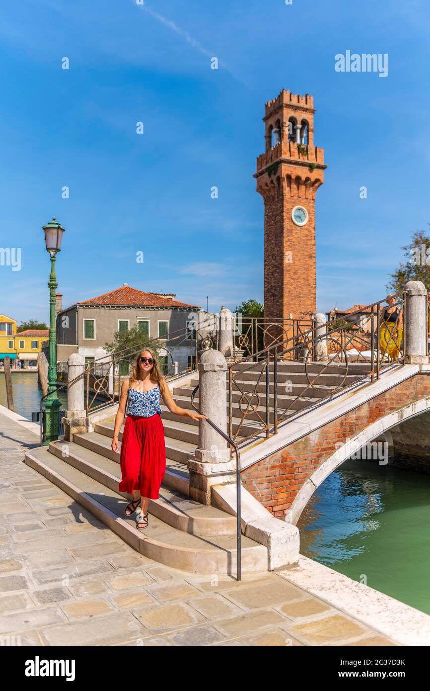 Junge Frau an einem Kanal, Häuser und Boote am Kanal Rio del Vetrai, Glockenturm St. Stefano, Murano, Venedig, Venetien, Italien Stockfoto