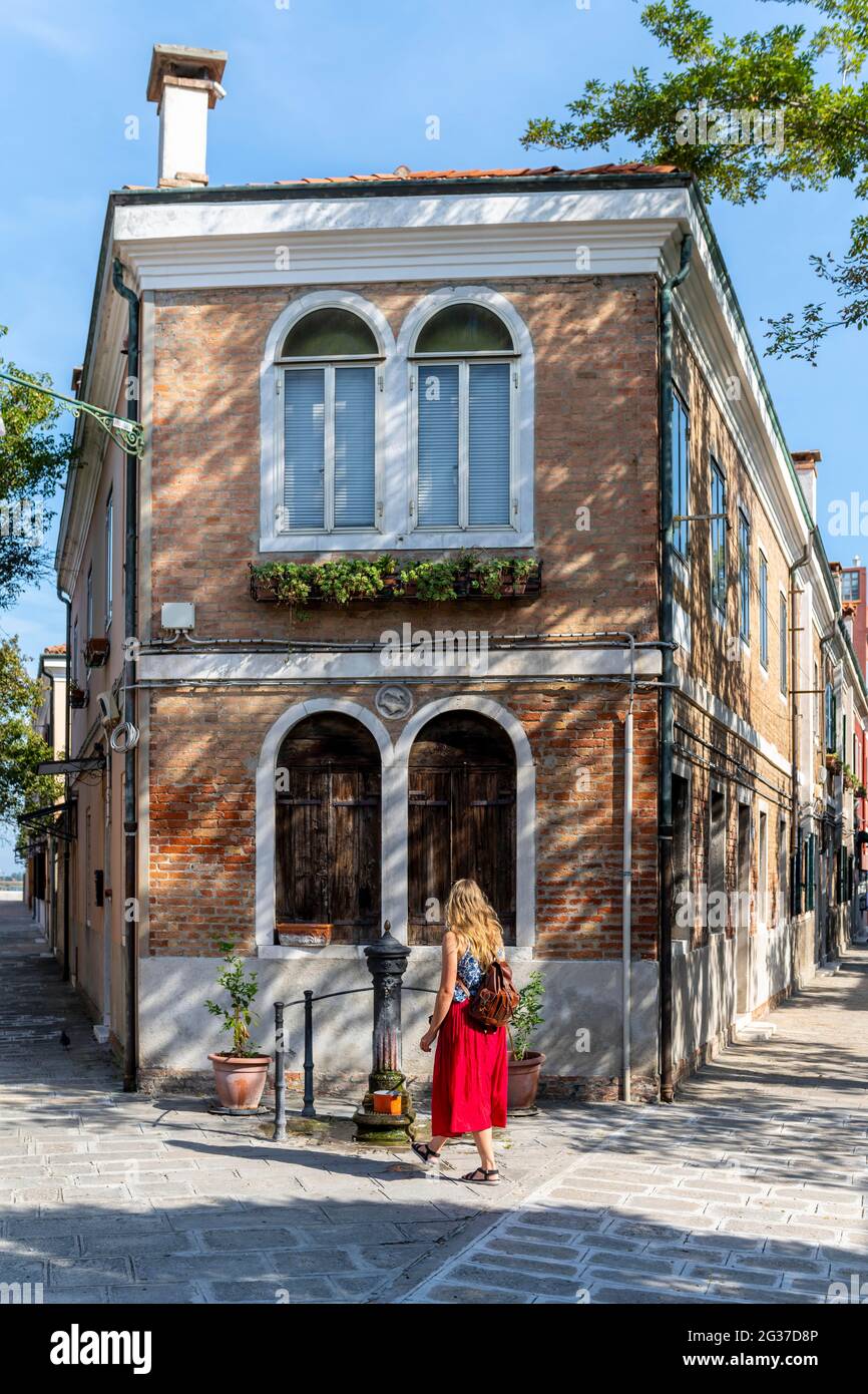 Tourist in roten Kleid vor einem Haus, Murano, Murano-Insel, Venedig, Venetien, Italien Stockfoto