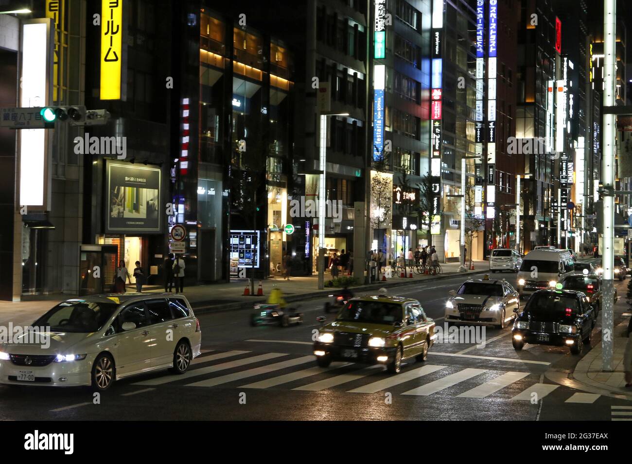 Beleuchtete Straße mit Neonlichtern und Autos im Ginza-Viertel, Tokio, Japan Stockfoto