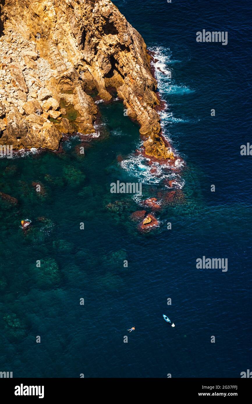 JAVEA, SPANIEN - 13. MAI 2021: SPORTSZENE IN DER NATUR, MANN SCHWIMMT NEBEN DEM KANU, AN DER COSTA BLANCA Stockfoto