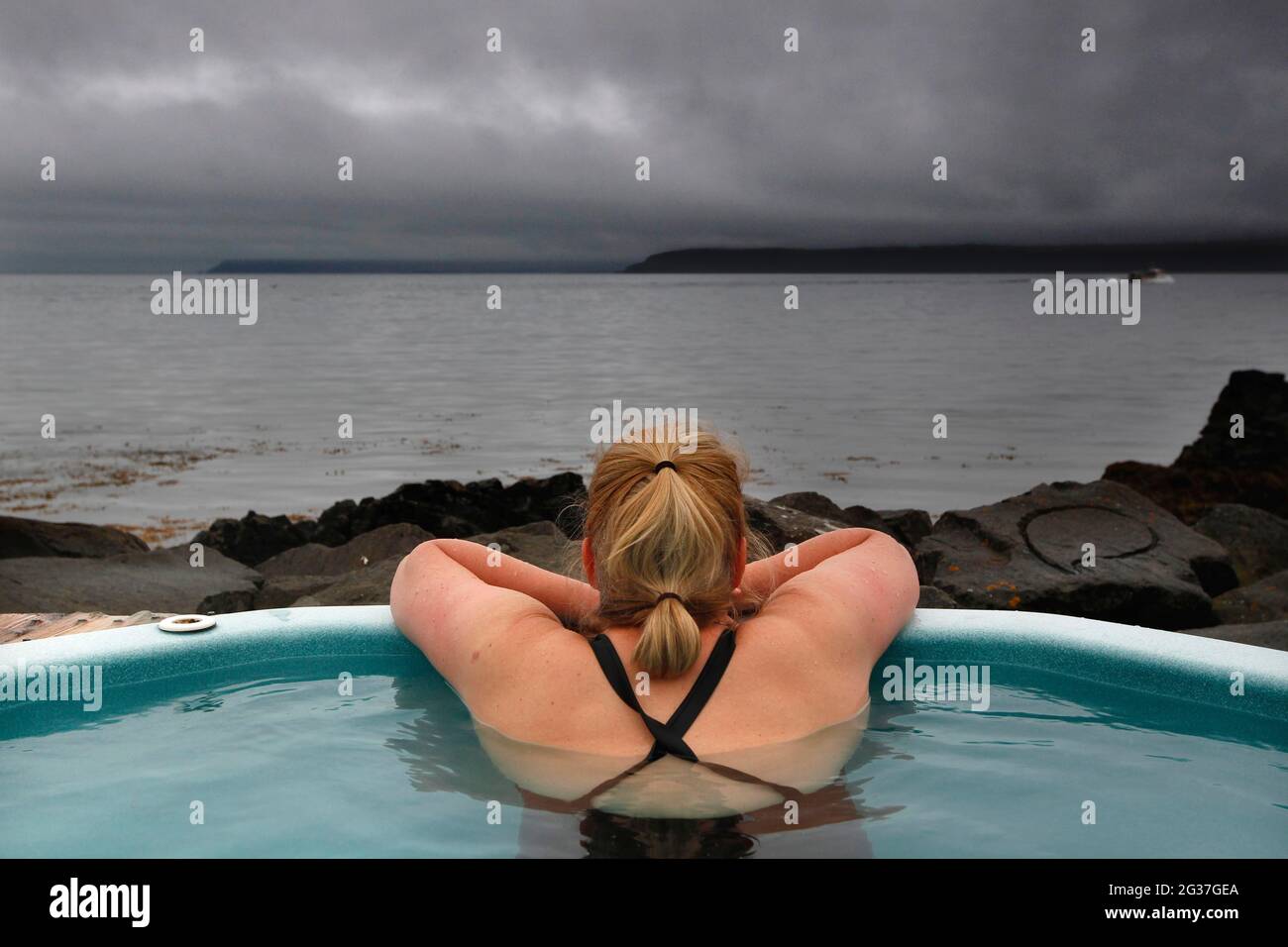 Frau im heißen Topf, geothermisches Bad am Atlantik, Rücken, Drangsnes, Vestfiroir, Westfjorde, Nordwest-Island, Island Stockfoto