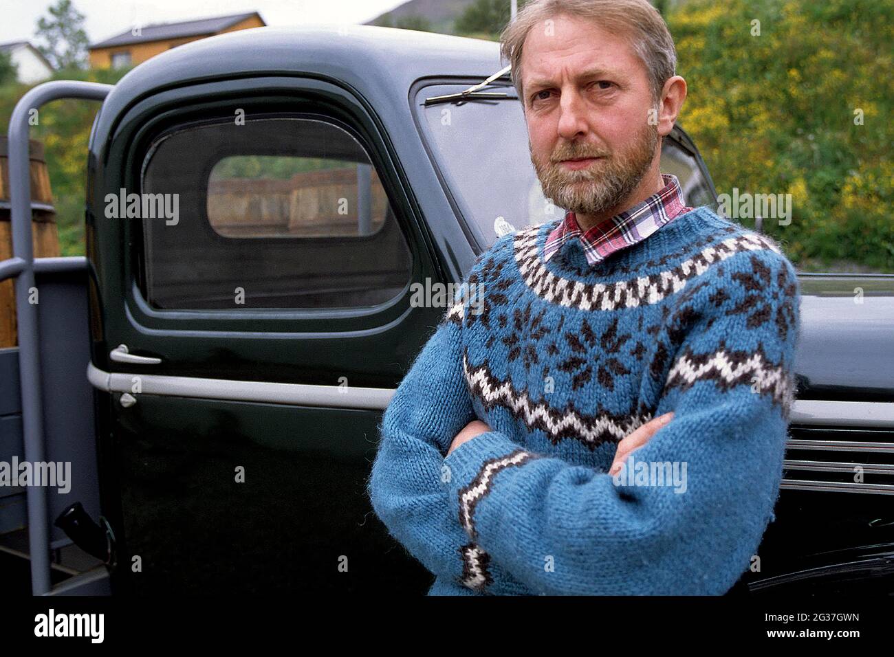 Mann im isländischen Pullover vor Oldtimer, Siglufjoerour, Nordisland, Island Stockfoto