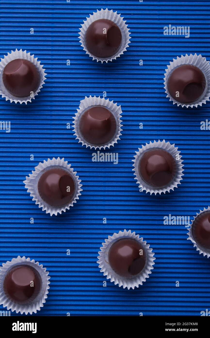Vertikale Schuss süßen braunen Schokolade Bonbons auf blauem Hintergrund. Stockfoto