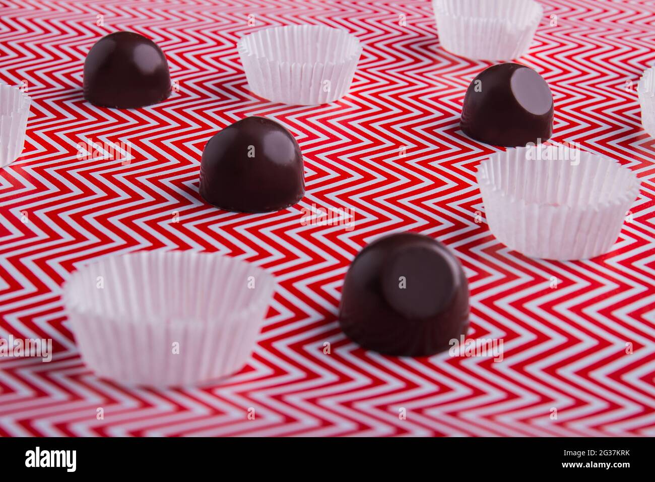 Nahaufnahme von Schokoladen-Bonbons mit Wraps auf rot-weißem Hintergrund. Stockfoto