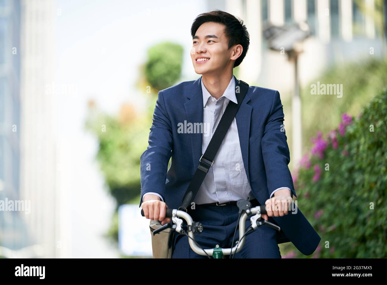 Junger asiatischer Geschäftsmann pendelt mit dem Fahrrad glücklich und lächelnd Stockfoto