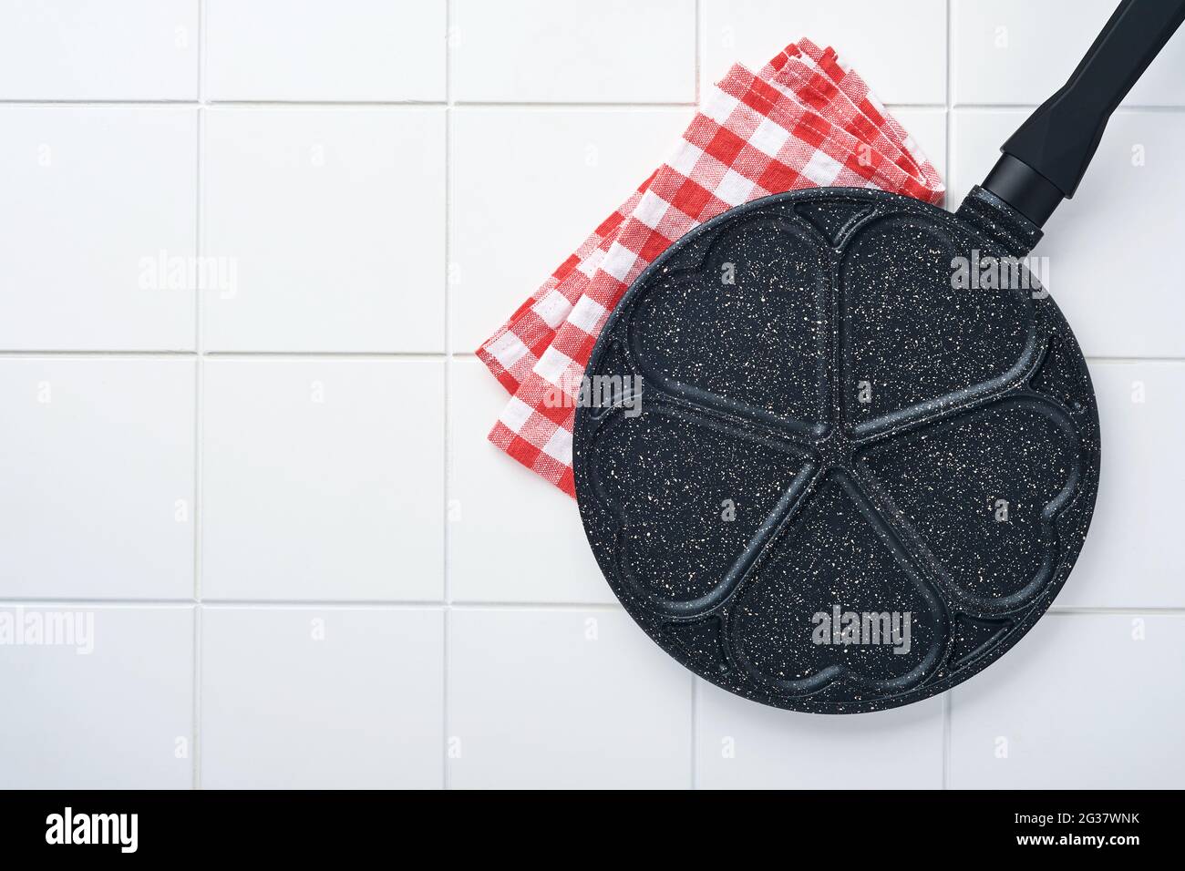 Leere Bratpfanne schwarz, Pfanne mit steinerner Antihaft-Beschichtung zum Backen von Pfannkuchen in Form von Frühstücksherzen und Zutaten auf grauem Betontisch BA Stockfoto