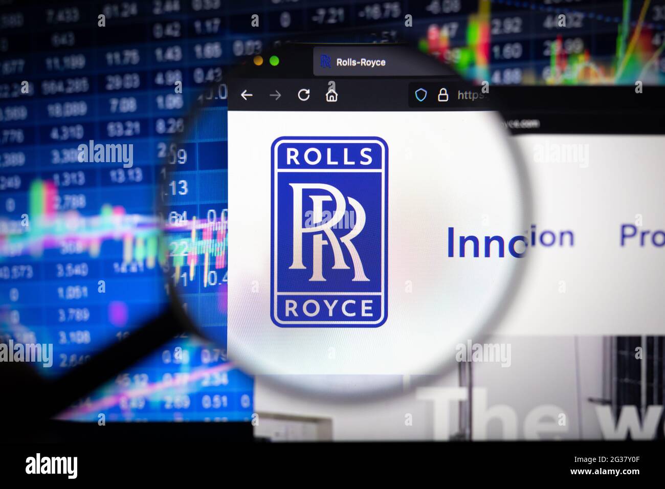 Rolls Royce Firmenlogo auf einer Website mit verschwommenen Börsenentwicklungen im Hintergrund, die auf einem Computerbildschirm durch eine Lupe gesehen werden Stockfoto