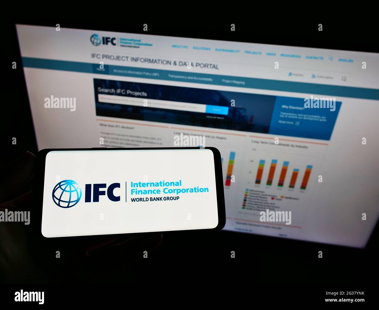 Person mit Mobiltelefon und Logo der Entwicklungsbank International Finance Corporation (IFC) auf dem Bildschirm vor der Webseite. Konzentrieren Sie sich auf die Telefonanzeige. Stockfoto