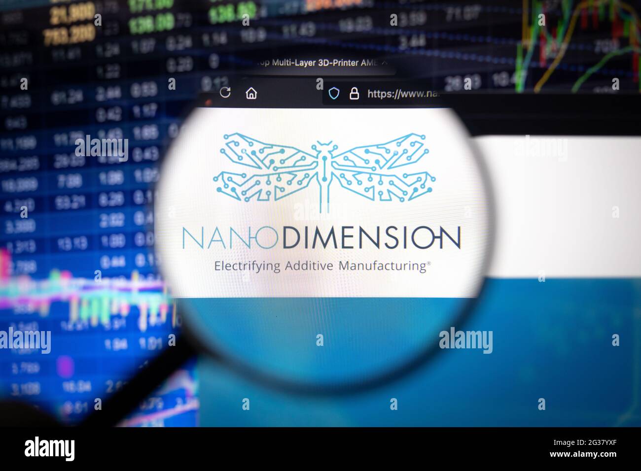 Nano Dimension Firmenlogo auf einer Website mit verschwommenen Börsenentwicklungen im Hintergrund, die auf einem Computerbildschirm durch eine Lupe gesehen werden Stockfoto
