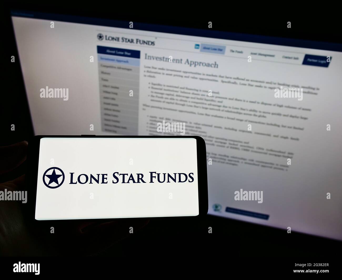 Person, die ein Mobiltelefon mit dem Logo der amerikanischen Investmentgesellschaft Lone Star Funds auf dem Bildschirm vor der Unternehmenswebseite hält. Konzentrieren Sie sich auf die Telefonanzeige. Stockfoto