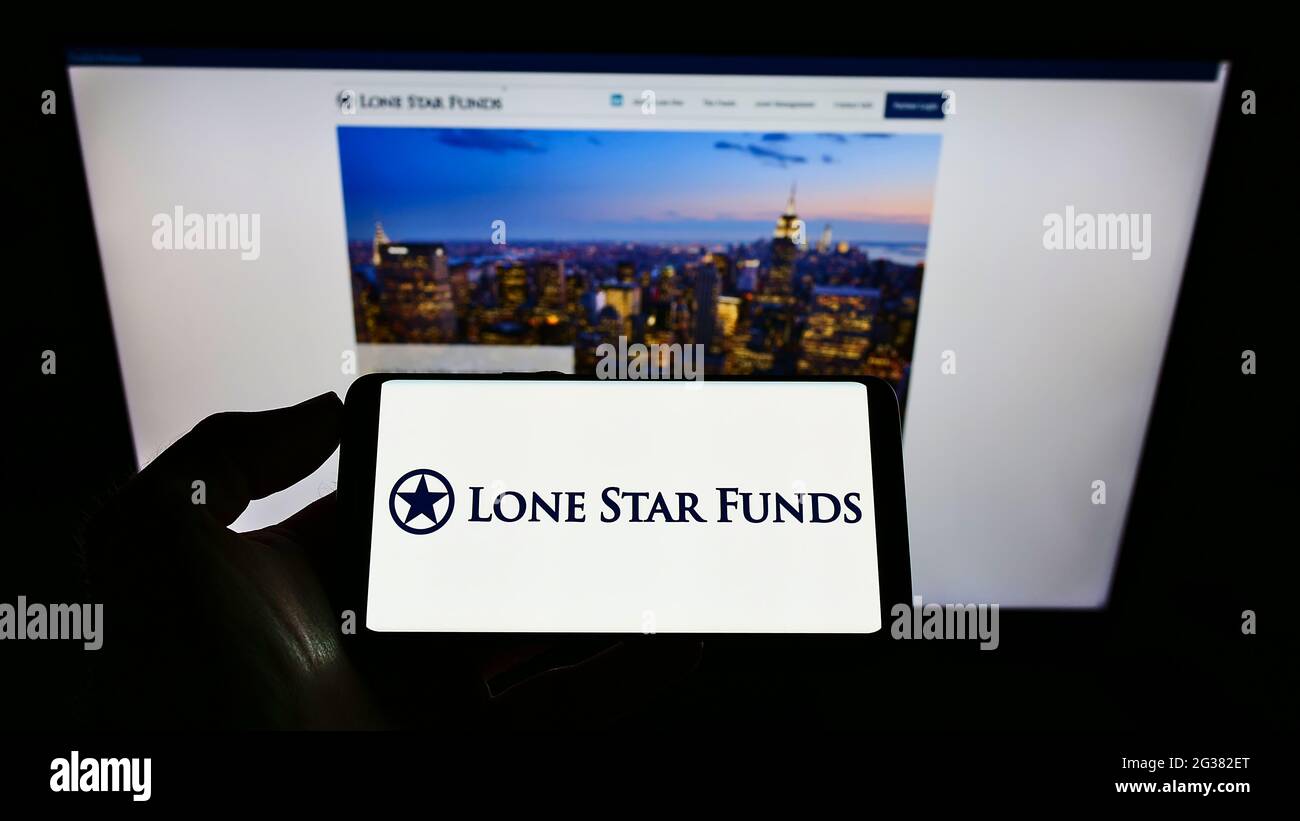 Person, die ein Mobiltelefon mit dem Logo der US-Investmentgesellschaft Lone Star Funds auf dem Bildschirm vor der Business-Webseite hält. Konzentrieren Sie sich auf die Telefonanzeige. Stockfoto