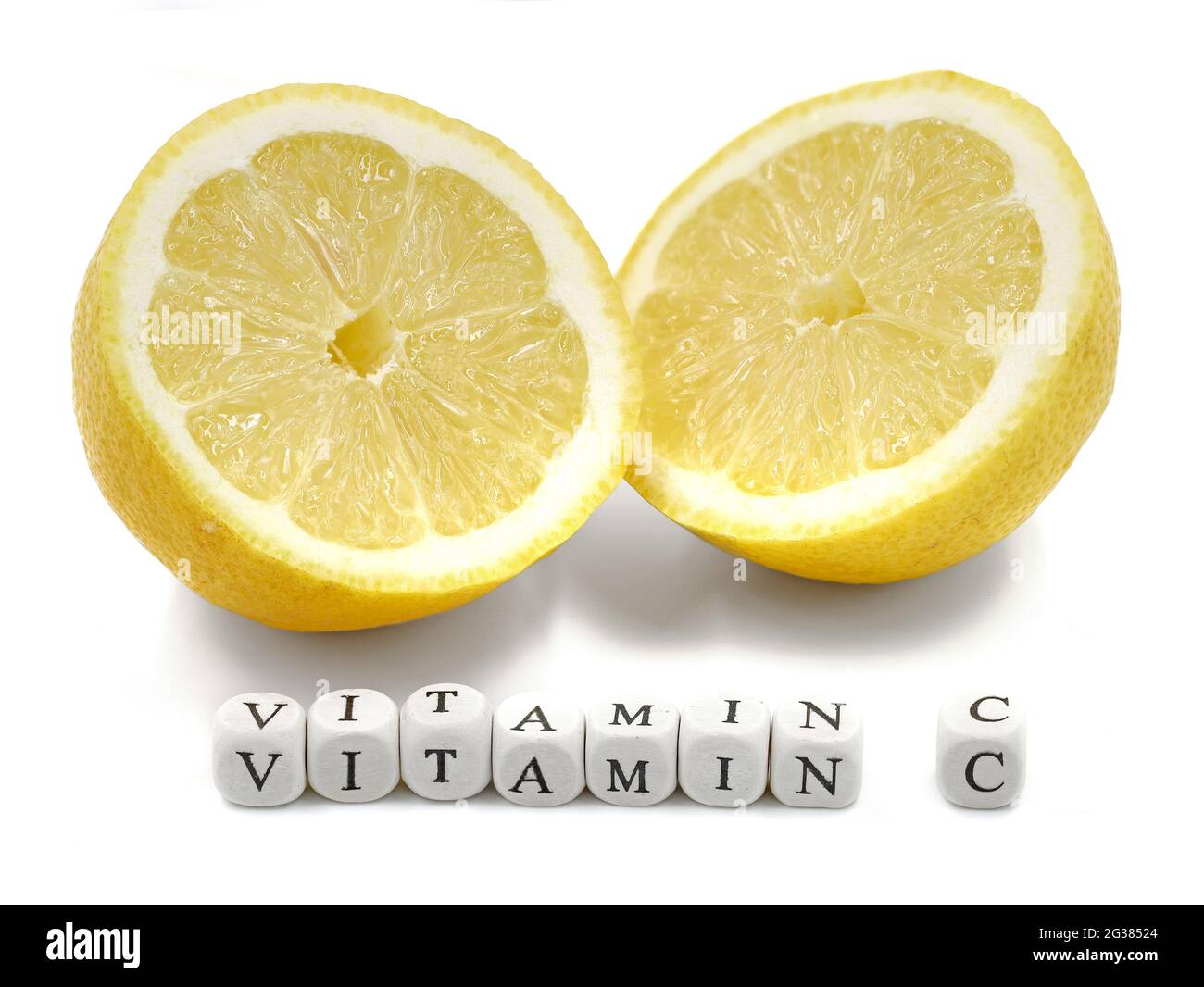 Frisch geschnittene reife Zitrone mit VITAMIN C-Wort aus Mini-Buchstabenwürfeln auf weißem Hintergrund isoliert Stockfoto