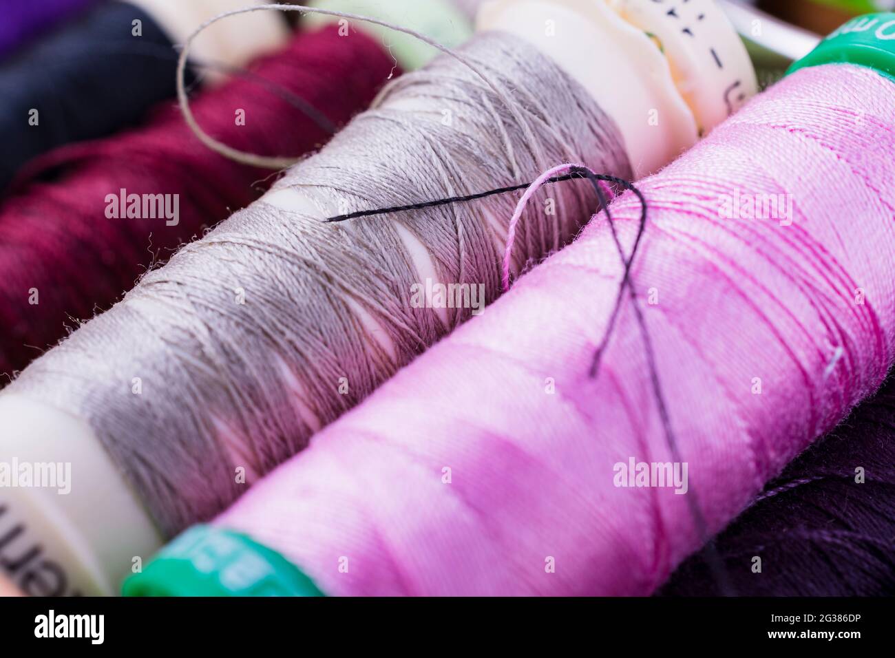 Spulen mit bunten Fäden auf dem Schreibtisch. Schneiderarbeit Stockfoto