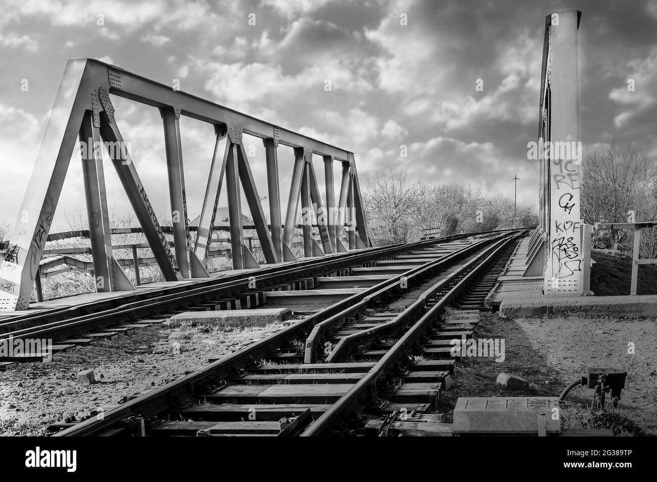 Struktur der grauen Metalleisenbahn-Brücke für den Zug. Alte Eisenbahnbrücke über das Wasser, in schwarz und weiß Stockfoto