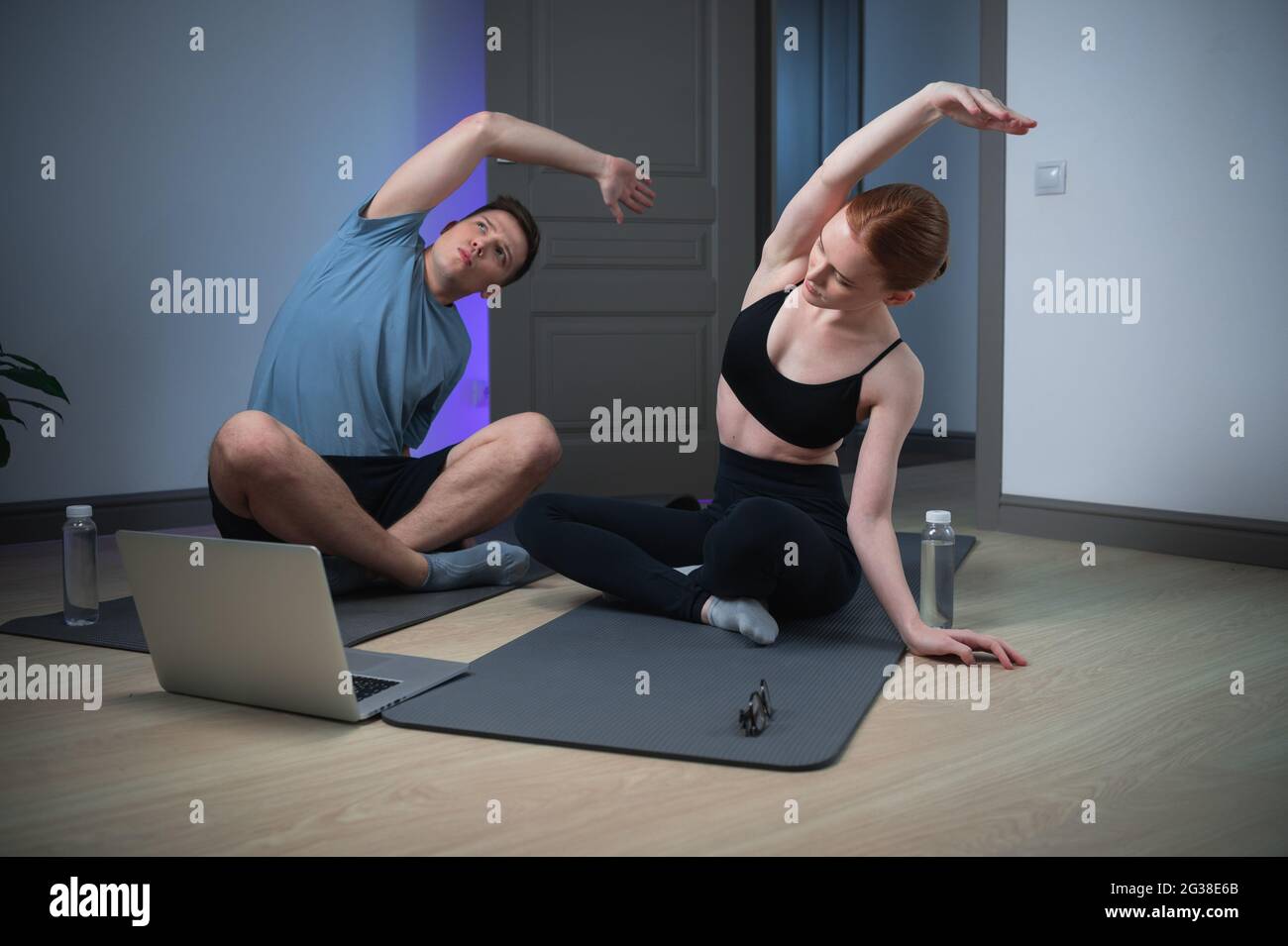 Während der Selbstisolation führt die Familie der Athleten zu Hause Online-Training durch, die Lektion beginnt mit Stretching, sie strecken ihre Arme und die Seite. Stockfoto