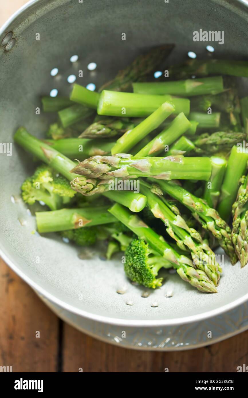 Gedünsteter Brokkoli und grüner Spargel in Sieb Stockfoto