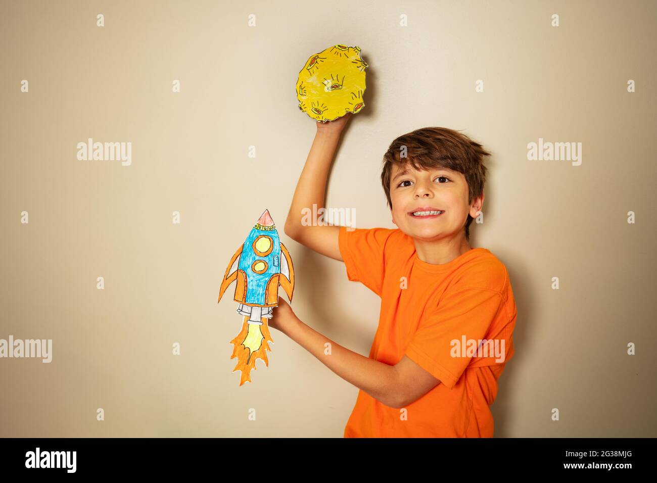 Lächelnder Junge mit Rakete und Planet aus Papier Stockfoto